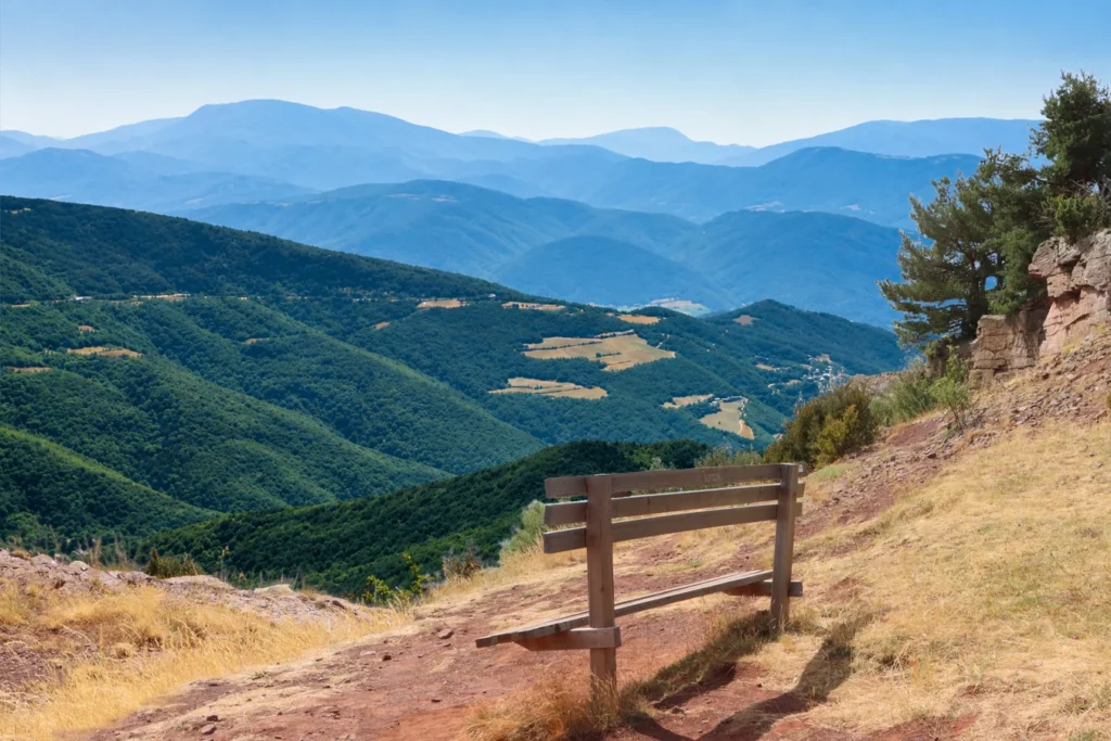 Small bench overlooking the Pyrenees, with a narrow path winding uphill