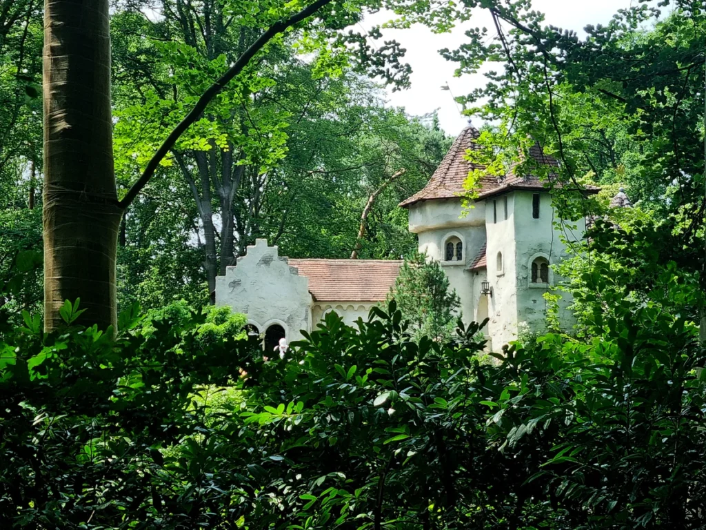 Sleeping Beauty's Castle in the Fairytale Forest at Efteling theme park, surrounded by green trees and bushes.